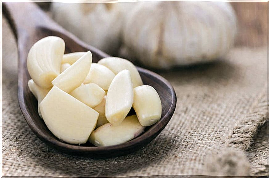 Wooden spoon with peeled garlic cloves.