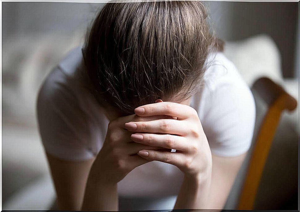 Overwhelmed girl covering her face with her hands.