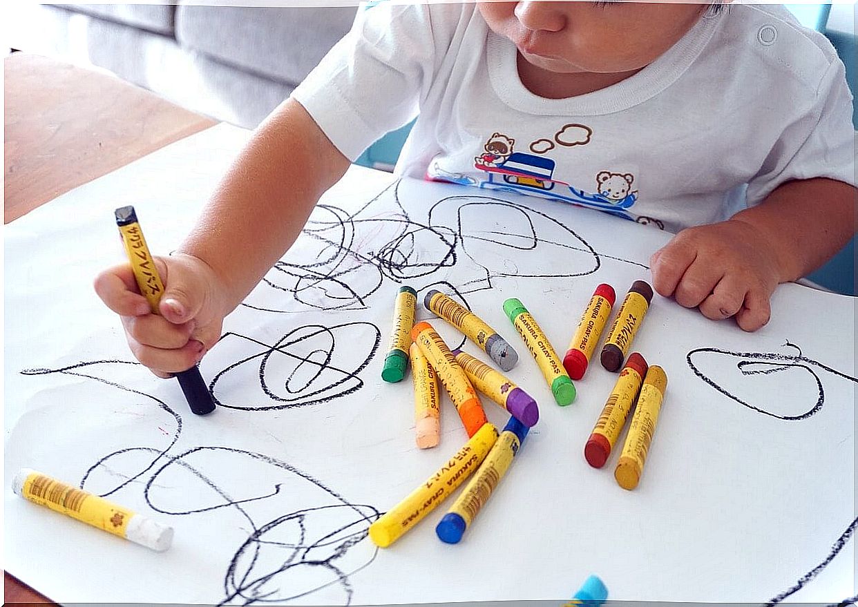 Child drawing with different colored paints.