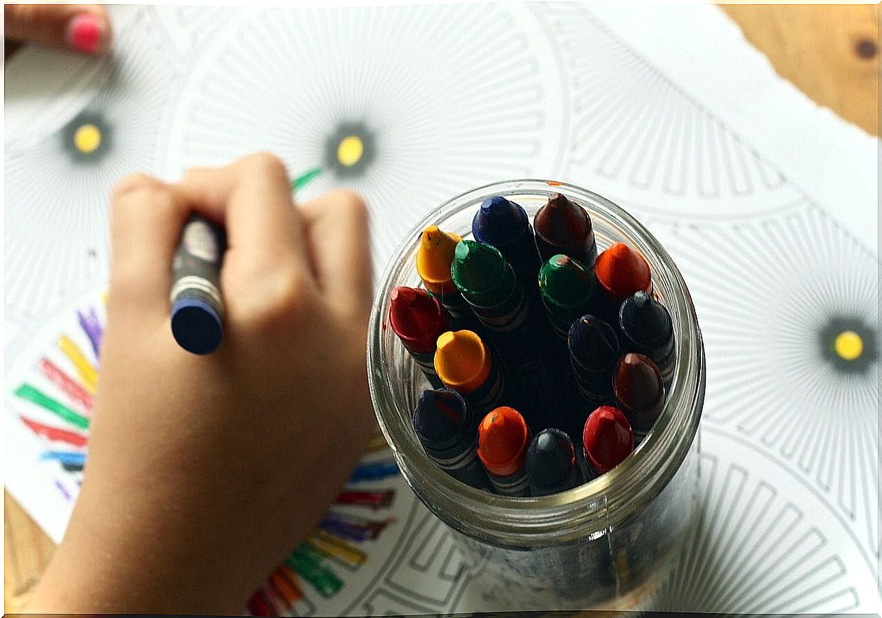 A child's hand drawing and colored paints to reap all the benefits of drawing.