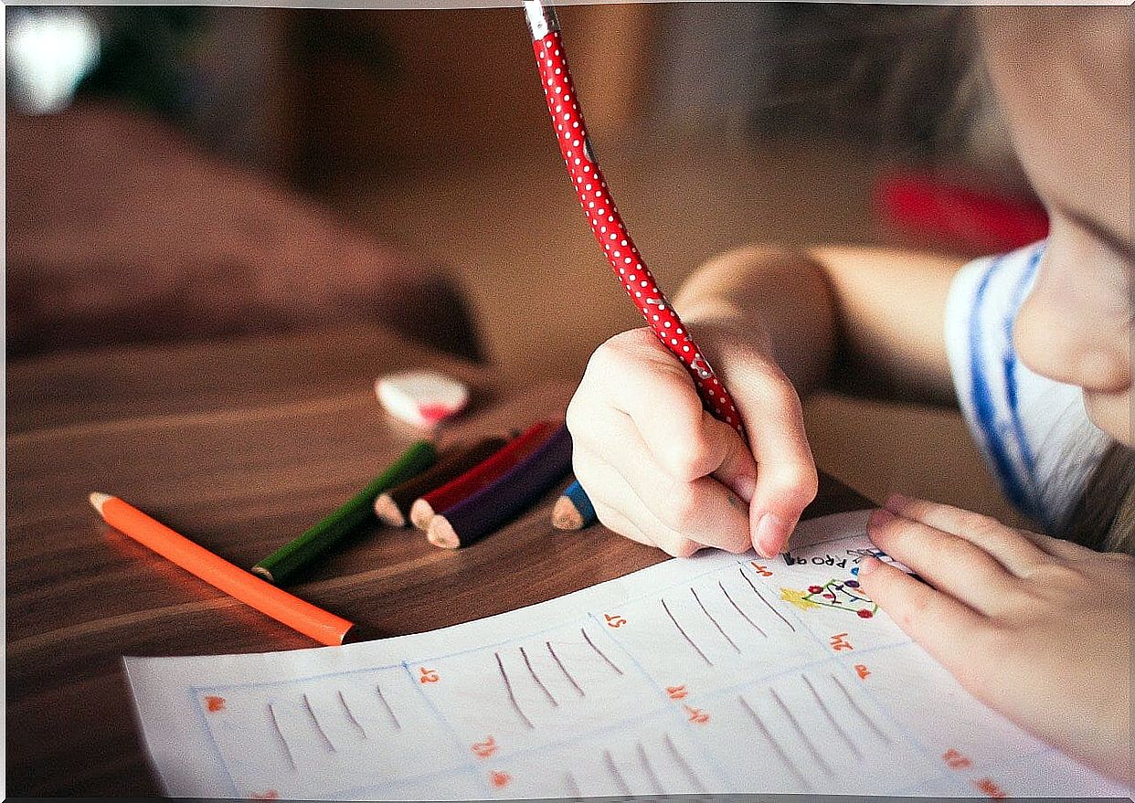 Child drawing with a pencil on a sheet to take advantage of all the benefits of drawing.