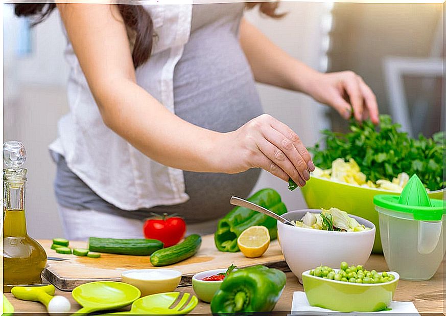 Pregnant woman cooking with vegetables