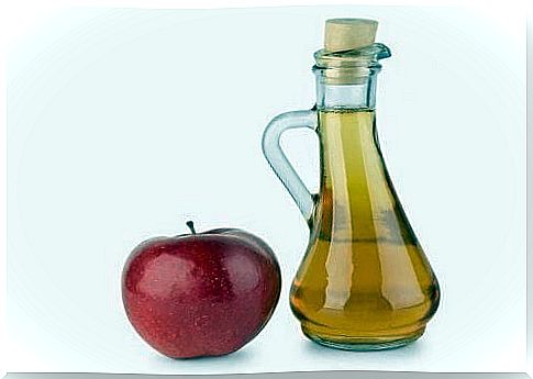 Jar of apple cider vinegar next to a red apple