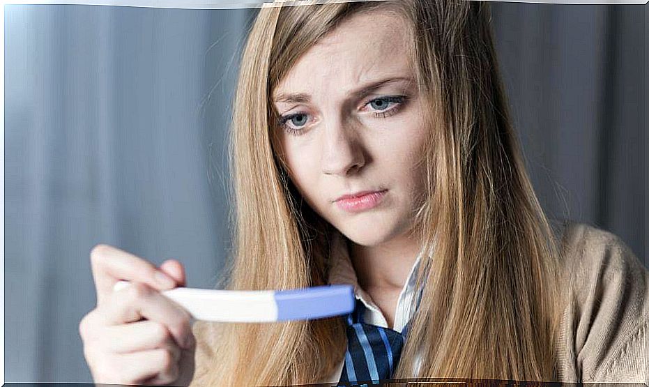 Woman looking at a pregnancy test.  Types of abortion.